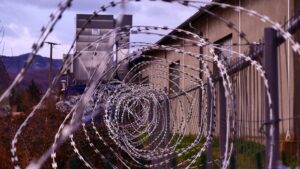 Close up view of a barbed wire fence surrounding a prison yard.