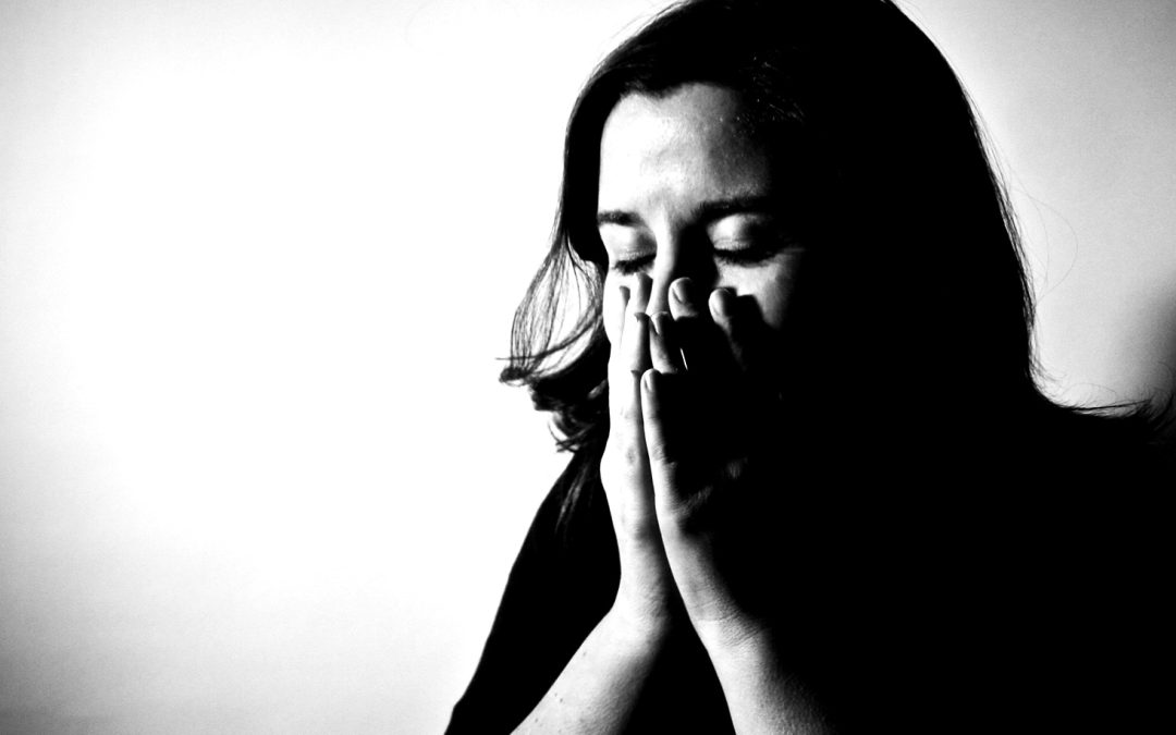 A black and white image of a hispanic woman with her face between her hands