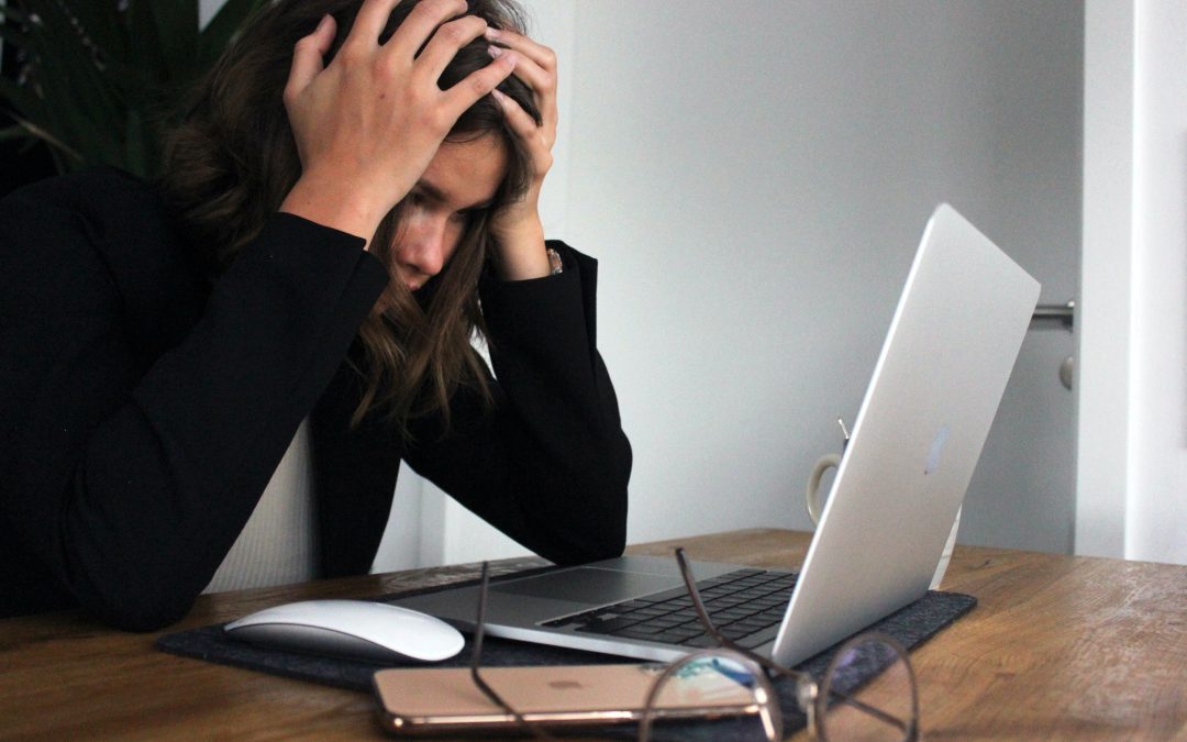 Workplace stress : A woman sitting in front of her computer with her head in her hands -