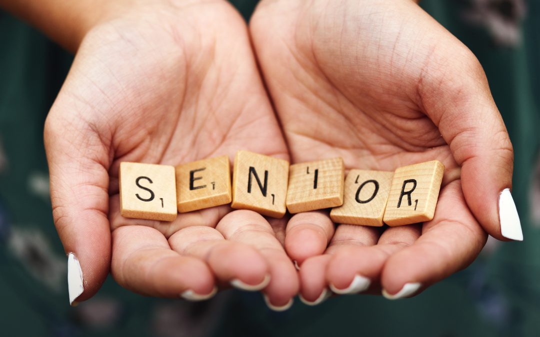 girl with manicured fingernails holding scrabble letters spelling the word SENIOR in the palms of her cupped hands