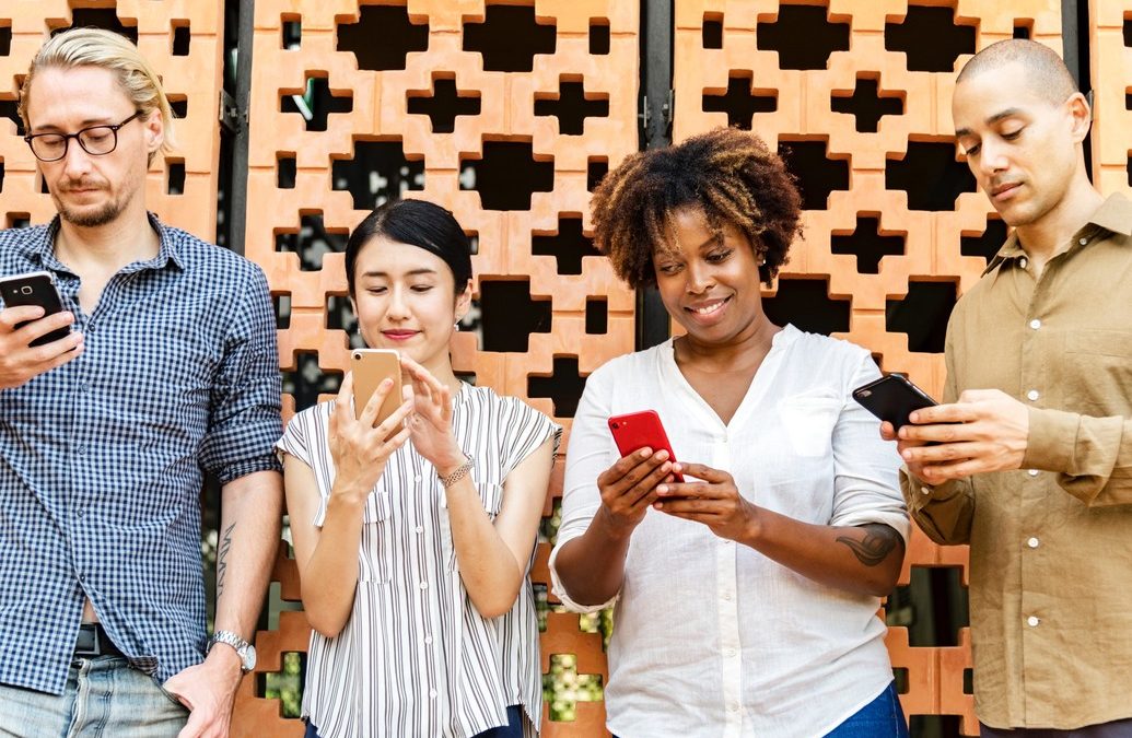 social media and mental health: 4 people standing side by side staring at their smartphones