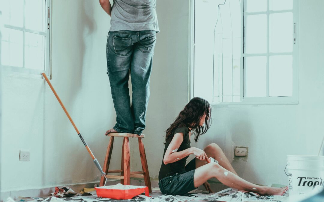 A couple painting the interior of a house with white walls