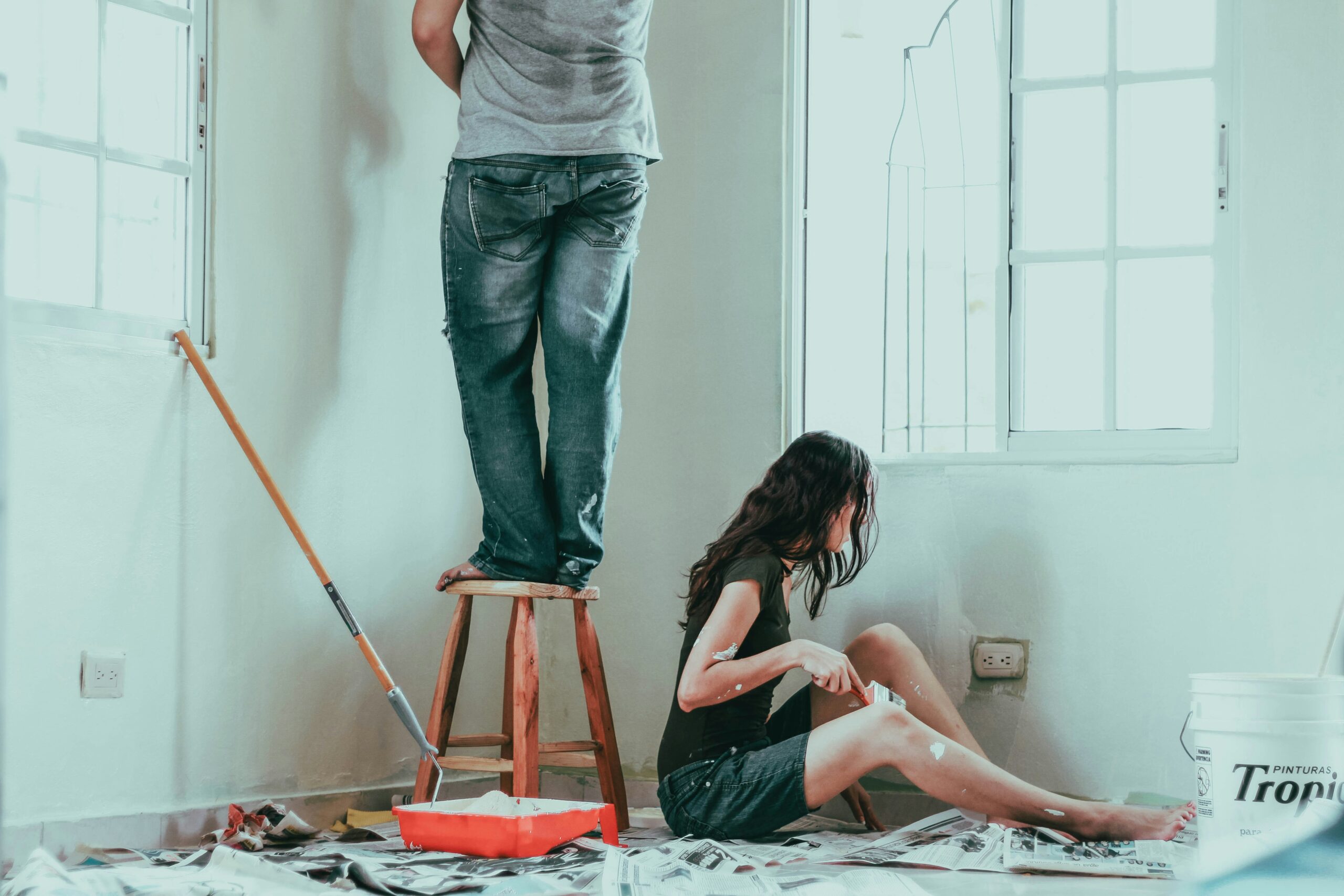 A couple painting the interior of a house with white walls