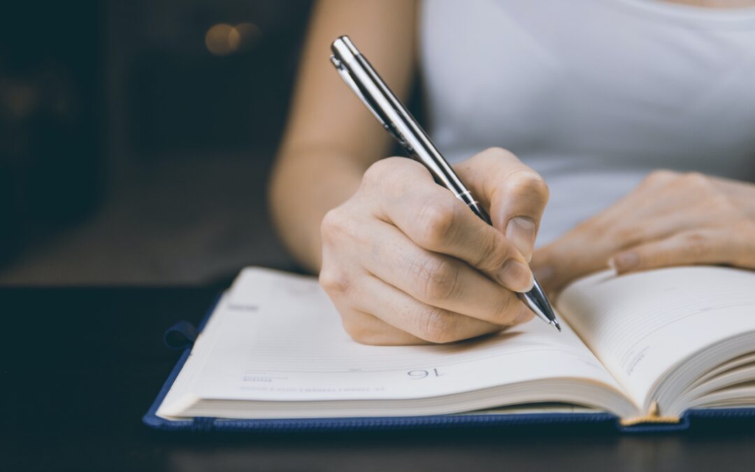Photo of Person Writing on Notebook