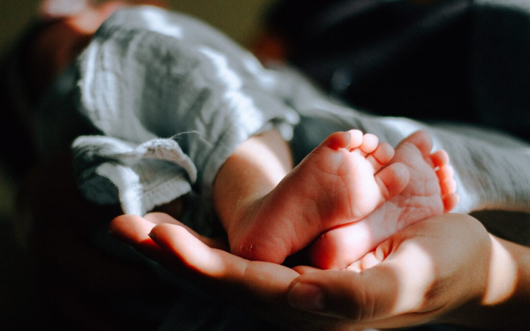 a person holding a baby and the feet are visible, so small.