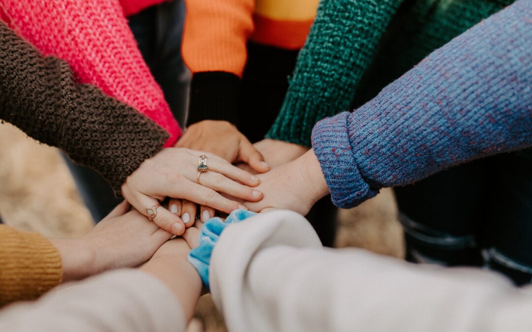 A group of people huddling placing hands on top of another