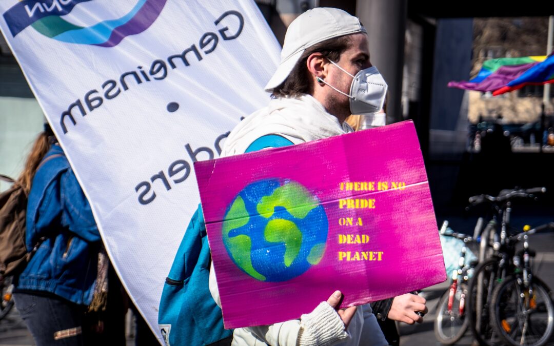 A man holding a benner saying "There is no pride in a dead planet"