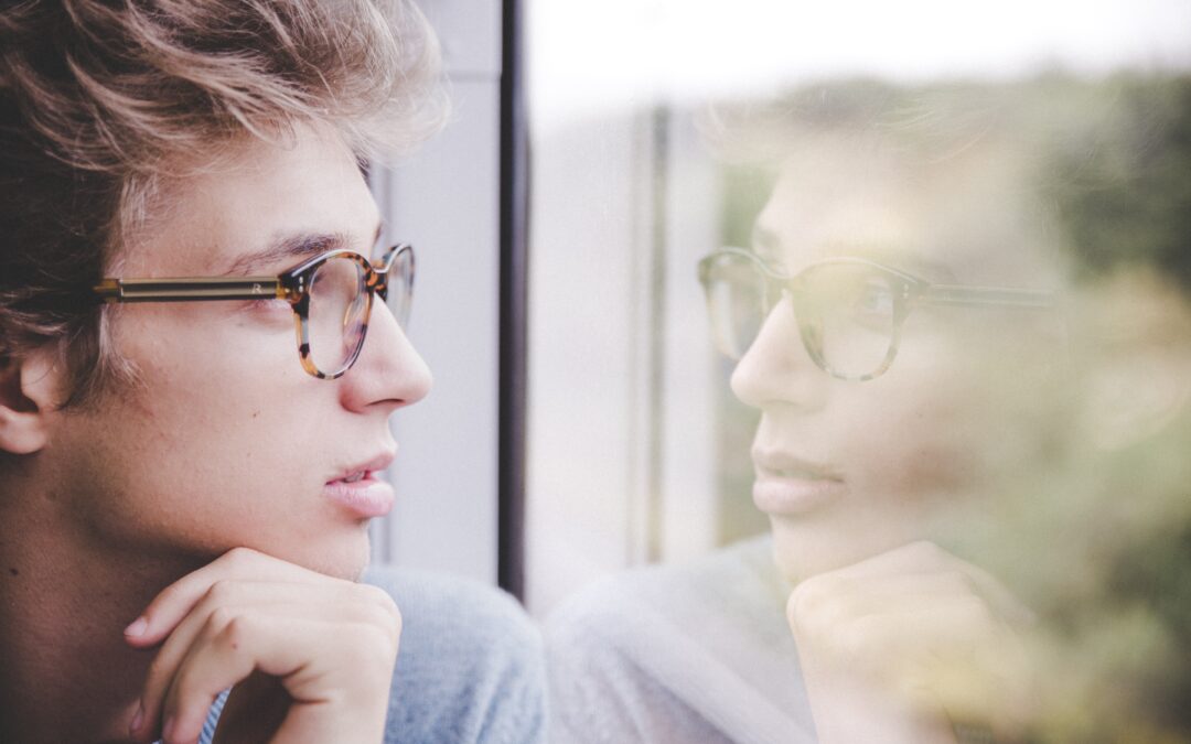Man wearing glasses looking out a window