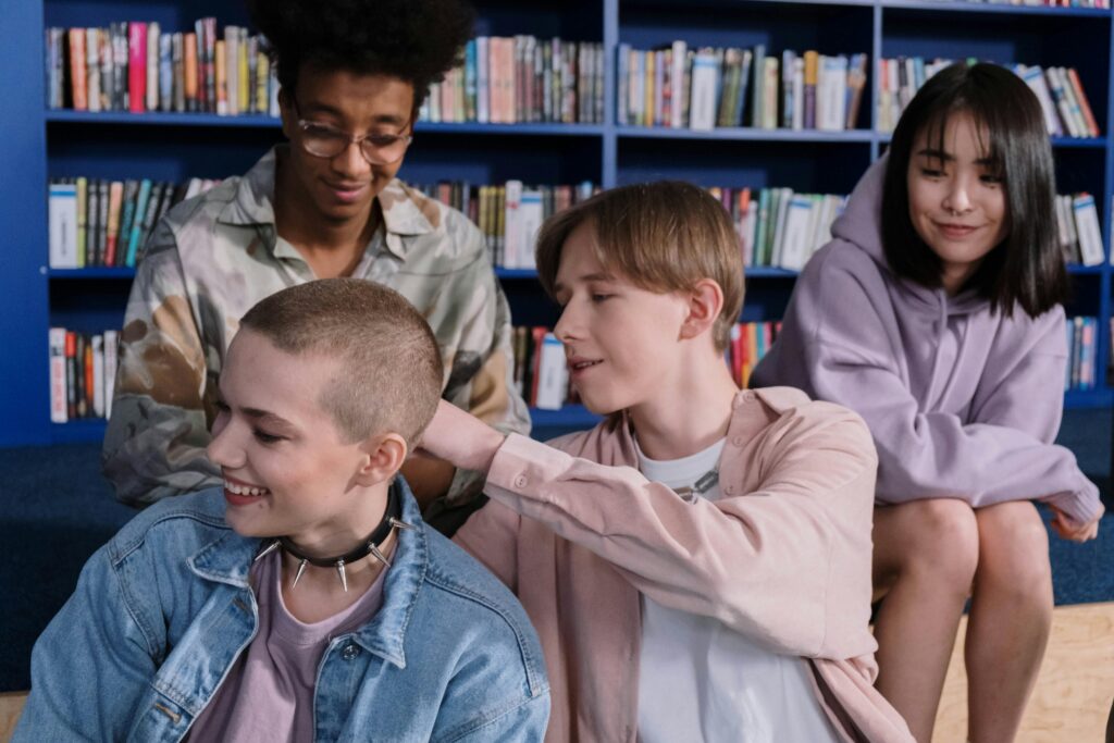 Four teenagers sit in a school library. They are of varying races.