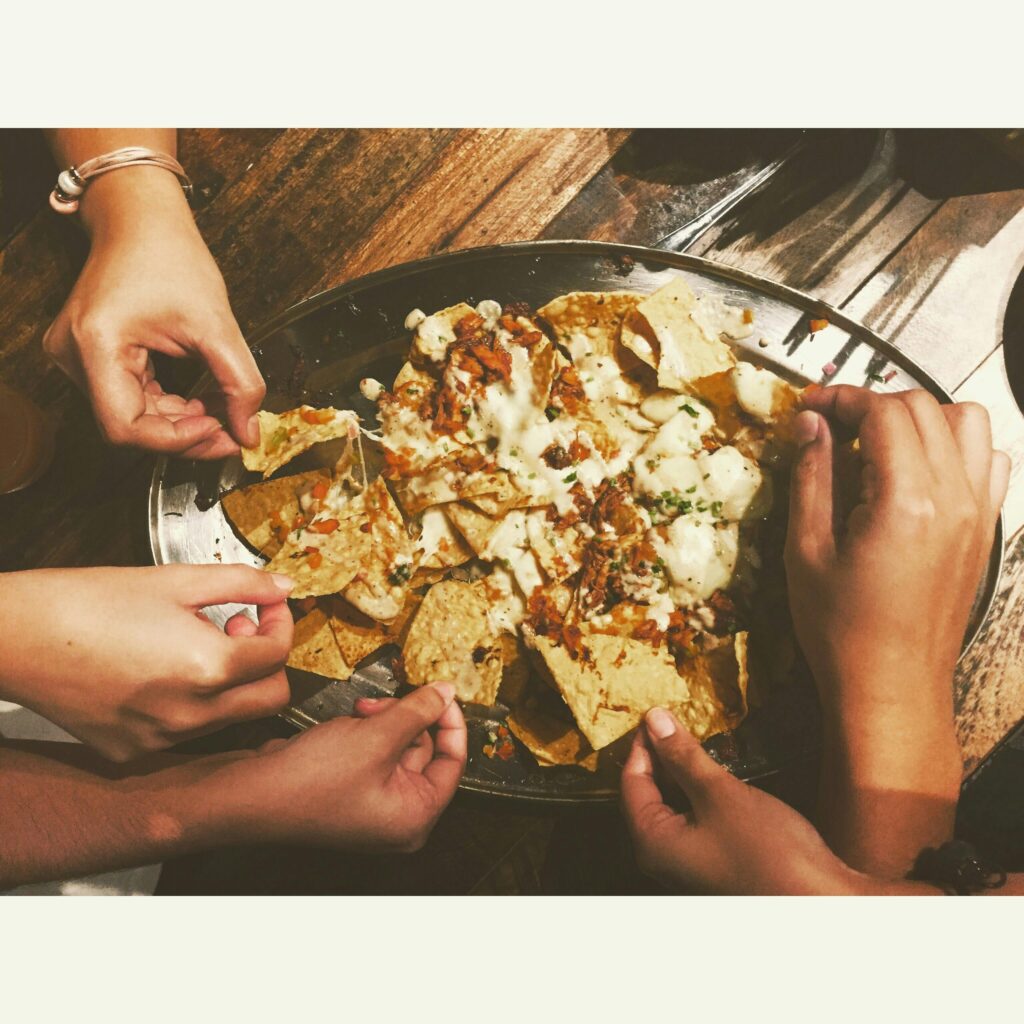 Hands reaching into a plate of nachos