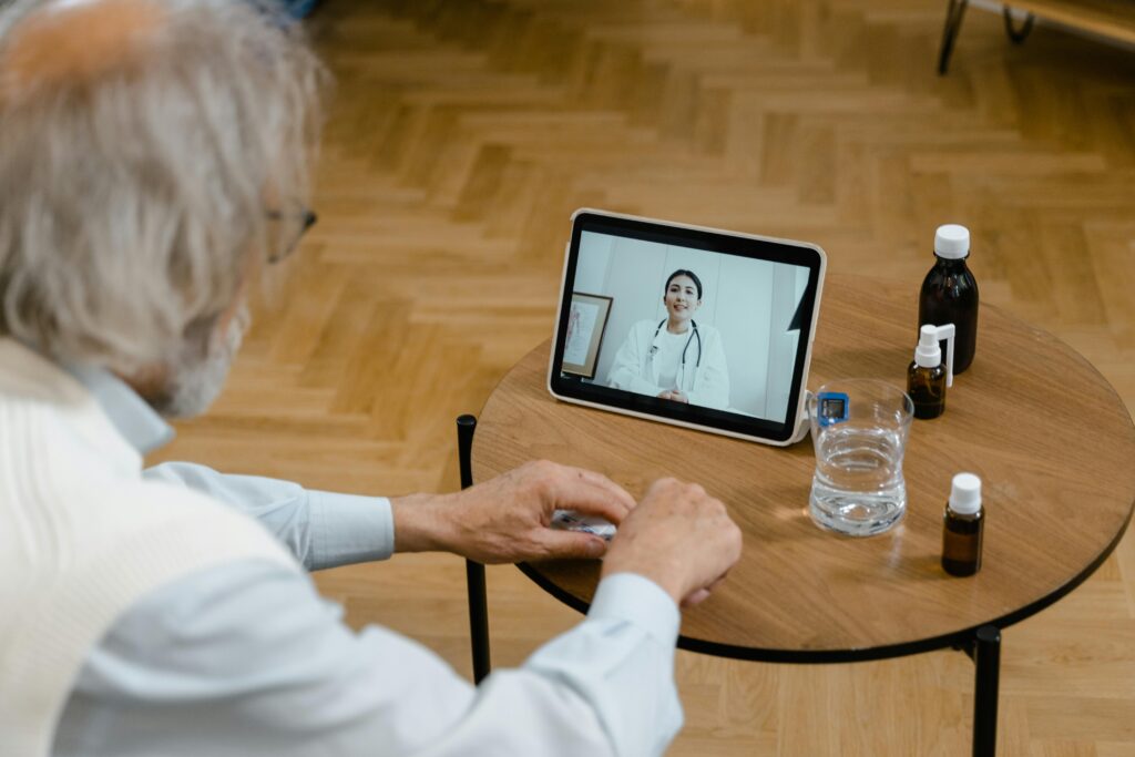 Doctor is performing a telehealth visit. Patient views doctor from a tablet on a side table. The doctor is an east asian woman.