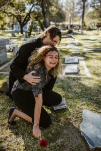 Two people breaking down at a tombstone